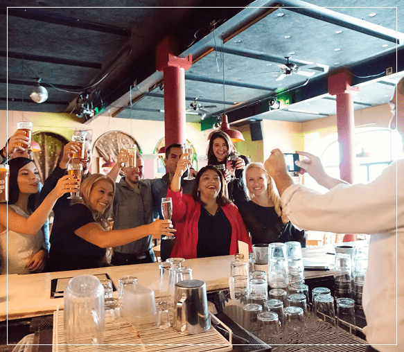 Group of friends cheering with glasses in a lively restaurant.