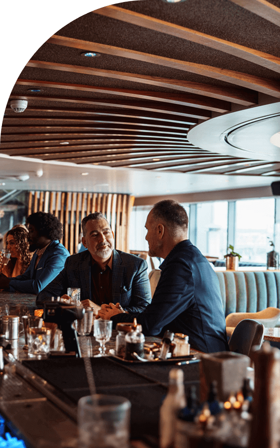 Two men engaged in a business discussion over drinks in a modern restaurant.