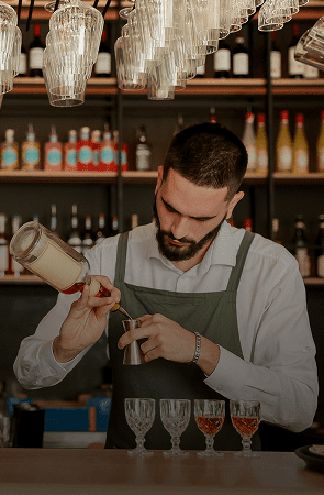 Bartender carefully pouring a cocktail into a glass.